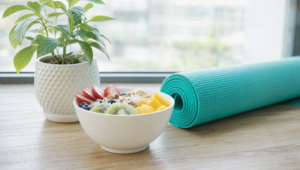 Ganzheitliches Gesundheitsdenken – Frisches Obst, Yoga-Matte und Pflanze am Fenster
